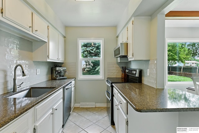 9704 Erskine St, Omaha, NE 68134 - kitchen with appliances with stainless steel finishes, light tile patterned floors, white cabinets, and backsplash