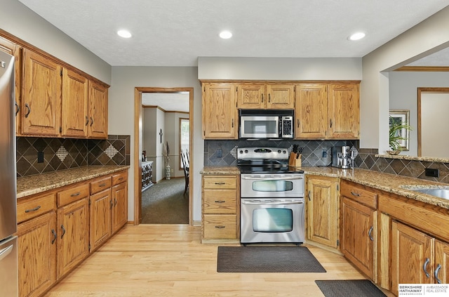 2468 N 148th St, Omaha, NE 68116 - kitchen with stainless steel appliances, light wood-type flooring, decorative backsplash, light stone counters, and recessed lighting