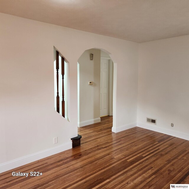 2134 S 48th St, Omaha, NE 68106 - spare room featuring arched walkways, wood finished floors, and baseboards