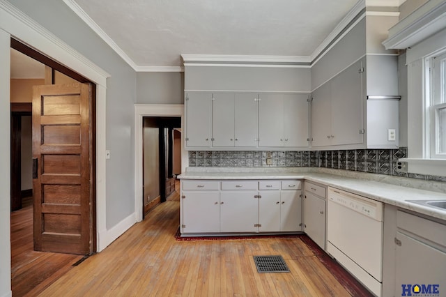 2524 S St, Lincoln, NE 68503 - kitchen featuring white dishwasher, light wood finished floors, decorative backsplash, light countertops, and ornamental molding