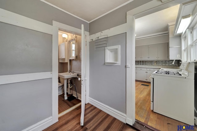 2524 S St, Lincoln, NE 68503 - kitchen featuring gas range gas stove, wood finished floors, crown molding, decorative backsplash, and baseboards