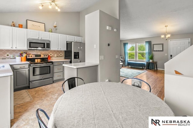 13518 Westport Cir, Bellevue, NE 68123 - kitchen featuring stainless steel appliances, lofted ceiling, a chandelier, light countertops, and gray cabinetry