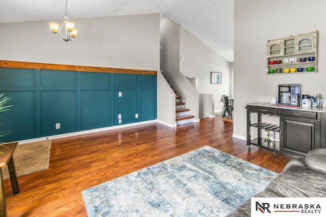 13518 Westport Cir, Bellevue, NE 68123 - living room featuring stairway, wood finished floors, a chandelier, a decorative wall, and high vaulted ceiling