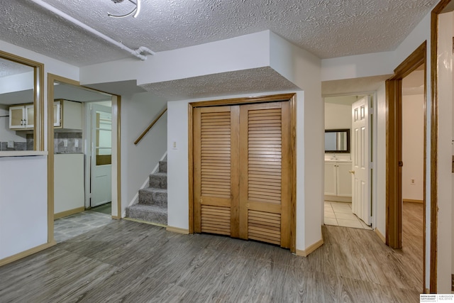 4459 F St, Omaha, NE 68107 - finished below grade area with wood finished floors, stairway, a textured ceiling, a sink, and baseboards