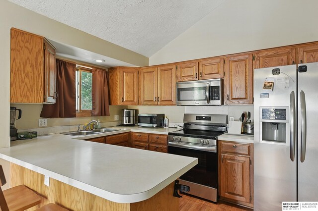 8853 N 82nd Ave, Omaha, NE 68122 - kitchen with appliances with stainless steel finishes, a sink, a peninsula, light countertops, and vaulted ceiling