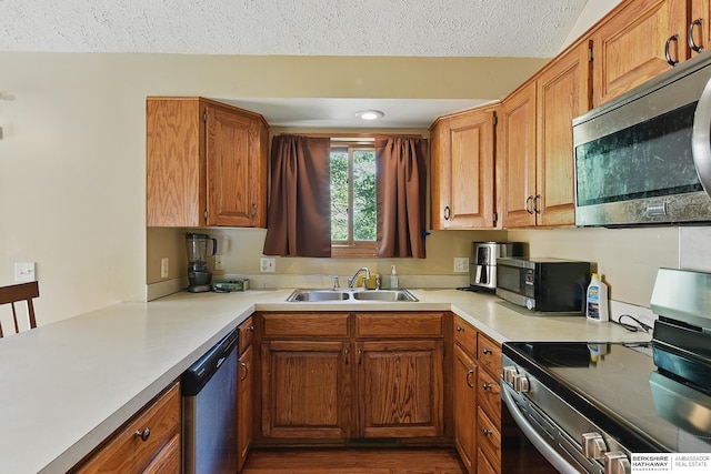 8853 N 82nd Ave, Omaha, NE 68122 - kitchen featuring stainless steel appliances, a sink, light countertops, brown cabinets, and a textured ceiling