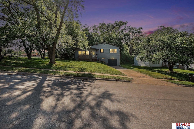 5704 N 68th St, Omaha, NE 68104 - split level home featuring concrete driveway, an attached garage, and a front lawn