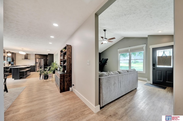 631 Overlook Ln, Beatrice, NE 68310 - living room with light wood finished floors, ceiling fan, a textured ceiling, baseboards, and lofted ceiling