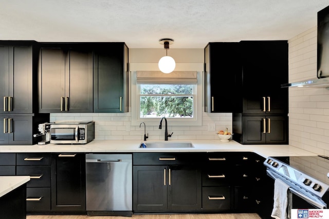 631 Overlook Ln, Beatrice, NE 68310 - kitchen with stainless steel appliances, a sink, backsplash, dark cabinets, and light countertops