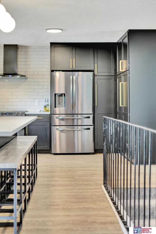 631 Overlook Ln, Beatrice, NE 68310 - kitchen with stainless steel fridge with ice dispenser, wall chimney exhaust hood, light wood-style flooring, and light countertops