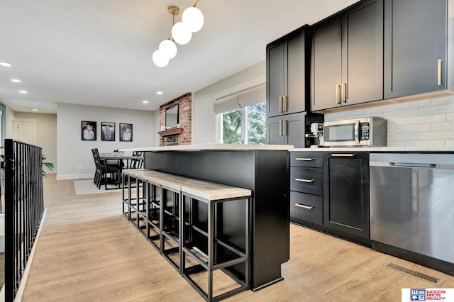 631 Overlook Ln, Beatrice, NE 68310 - kitchen with stainless steel appliances, light wood finished floors, light countertops, baseboards, and a kitchen bar