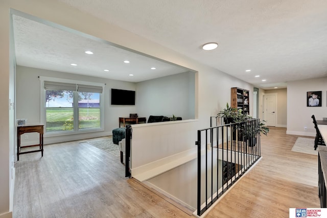 631 Overlook Ln, Beatrice, NE 68310 - hallway featuring an upstairs landing, light wood-type flooring, recessed lighting, a textured ceiling, and baseboards