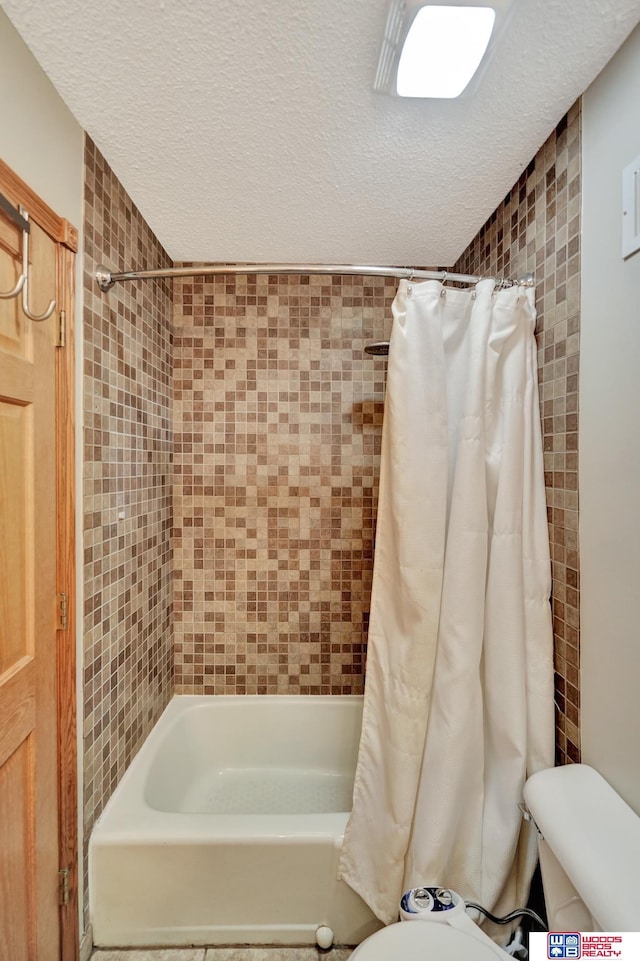 631 Overlook Ln, Beatrice, NE 68310 - full bathroom featuring toilet, shower / bath combo with shower curtain, and a textured ceiling