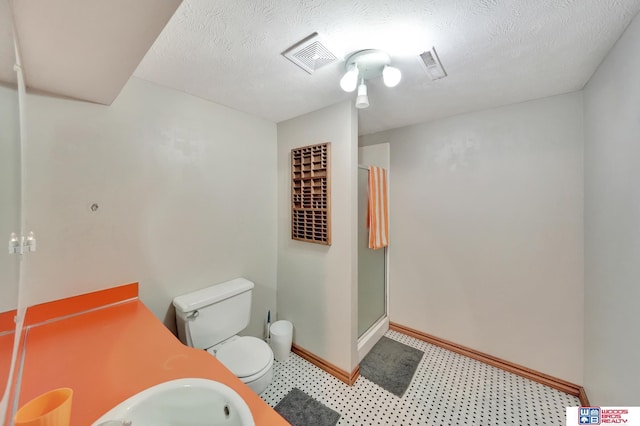 631 Overlook Ln, Beatrice, NE 68310 - bathroom with toilet, a stall shower, tile patterned floors, baseboards, and a textured ceiling