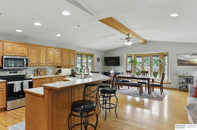 2442 E 2nd St, Fremont, NE 68025 - kitchen with stainless steel appliances, light wood finished floors, light countertops, a kitchen breakfast bar, and a kitchen island with sink