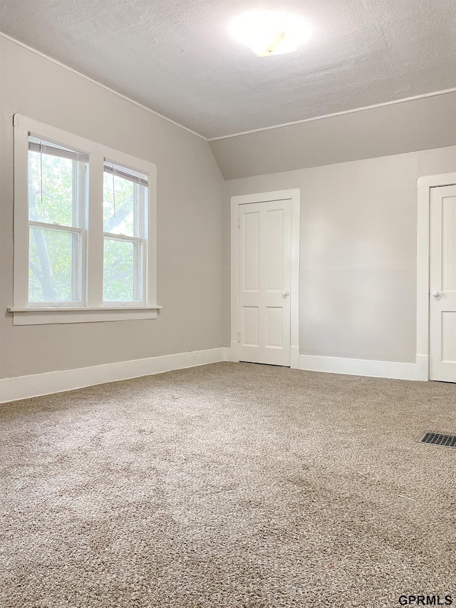 3719 X St, Omaha, NE 68107 - unfurnished room with carpet floors, vaulted ceiling, baseboards, and a textured ceiling
