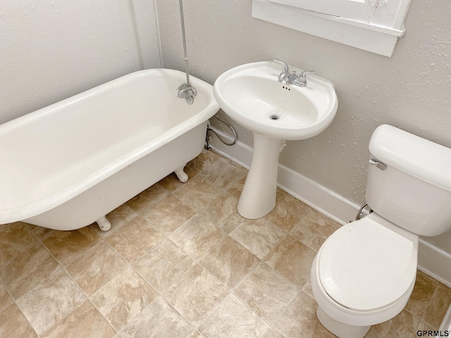 3719 X St, Omaha, NE 68107 - bathroom featuring a freestanding bath, toilet, and baseboards