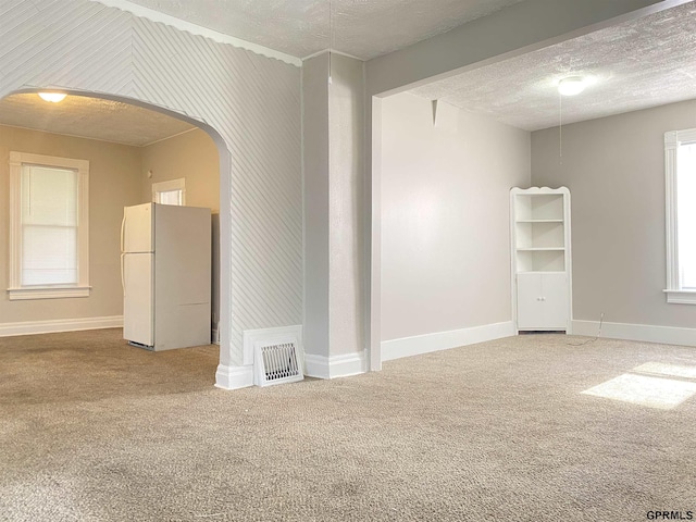 3719 X St, Omaha, NE 68107 - spare room featuring carpet flooring, a textured ceiling, baseboards, and arched walkways