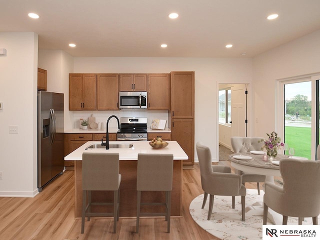 14802 Bruning St, Bennington, NE 68007 - kitchen with stainless steel appliances, a sink, brown cabinetry, light wood-style floors, and recessed lighting