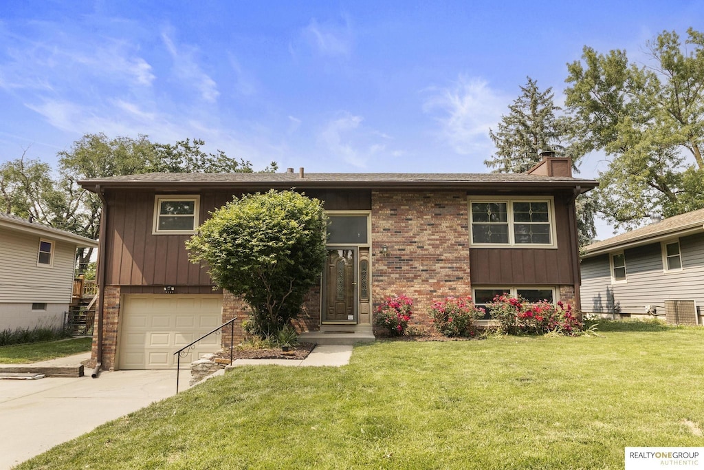 8206 Walnut Ln, Omaha, NE 68127 - bi-level home with a chimney, a garage, a front yard, and concrete driveway