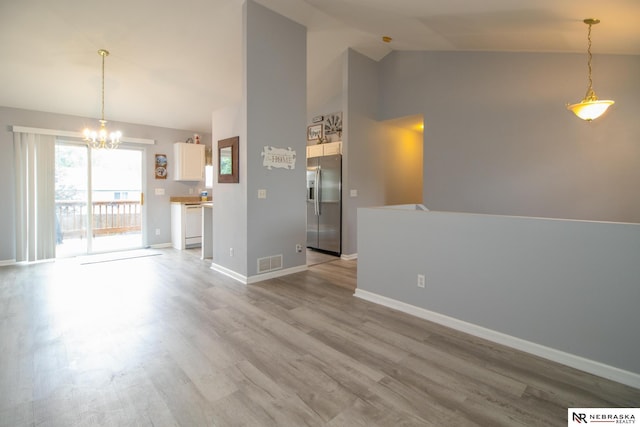 15417 Willit St, Bennington, NE 68007 - unfurnished living room with a chandelier, high vaulted ceiling, light wood-style floors, and baseboards