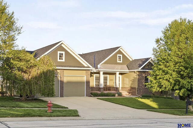 6920 NW 3rd St, Lincoln, NE 68521 - view of front of home featuring covered porch, brick siding, concrete driveway, a front lawn, and an attached garage