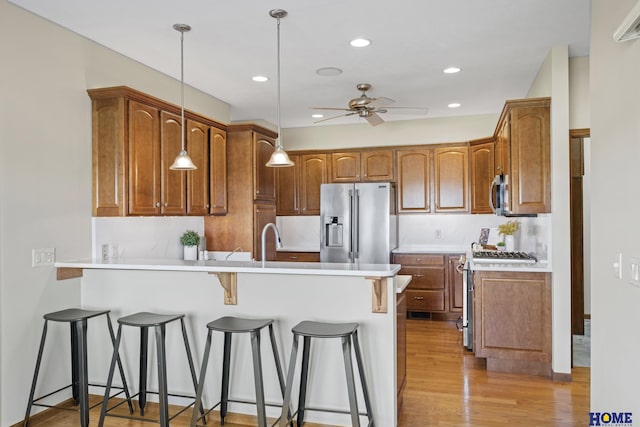 6920 NW 3rd St, Lincoln, NE 68521 - kitchen featuring stainless steel appliances, a peninsula, ceiling fan, a breakfast bar, and light wood-style flooring