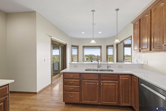 6920 NW 3rd St, Lincoln, NE 68521 - kitchen featuring stainless steel dishwasher, a sink, light wood-style flooring, light countertops, and pendant lighting