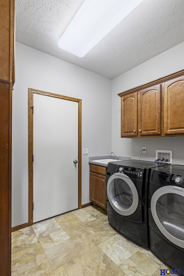 6920 NW 3rd St, Lincoln, NE 68521 - laundry room featuring cabinet space, washer and clothes dryer, a textured ceiling, baseboards, and stone finish flooring