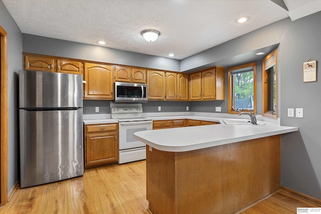 15212 Emmet St, Omaha, NE 68116 - kitchen with stainless steel appliances, a sink, a peninsula, brown cabinetry, and a textured ceiling