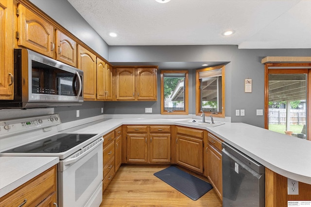 15212 Emmet St, Omaha, NE 68116 - kitchen with appliances with stainless steel finishes, a sink, light countertops, light wood-type flooring, and brown cabinetry