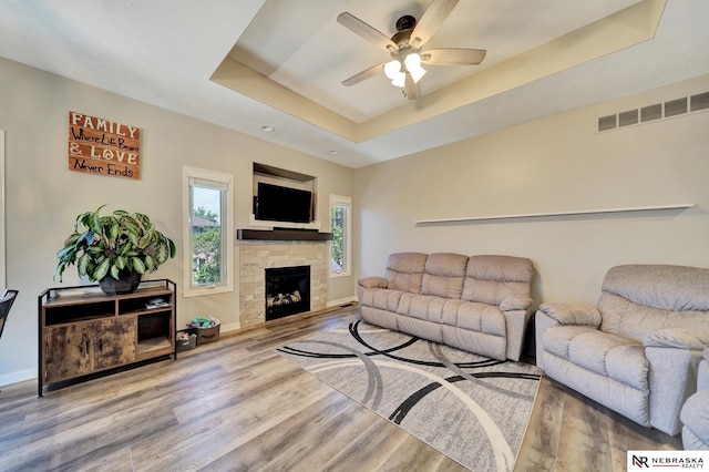 905 Chicory Ln, Hickman, NE 68372 - living area featuring a ceiling fan, wood finished floors, a tray ceiling, baseboards, and a stone fireplace