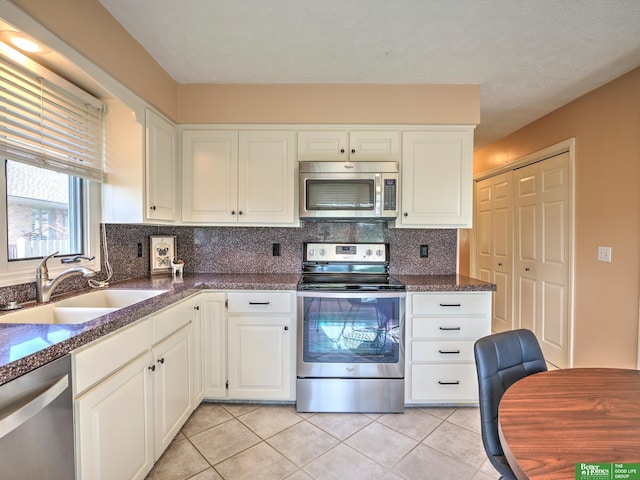 6212 Oak Hills Plz, Omaha, NE 68137 - kitchen featuring appliances with stainless steel finishes, a sink, light tile patterned flooring, tasteful backsplash, and white cabinets