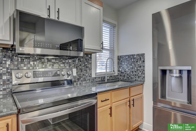 2864 Spaulding St, Omaha, NE 68111 - kitchen featuring appliances with stainless steel finishes, a sink, decorative backsplash, and dark stone countertops