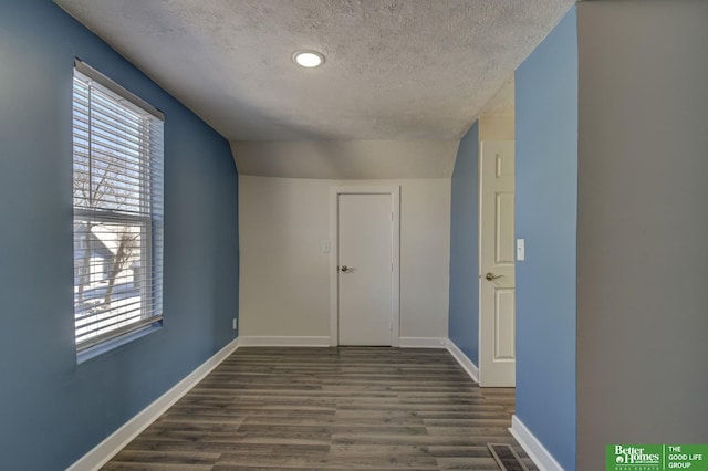 2864 Spaulding St, Omaha, NE 68111 - unfurnished bedroom featuring a textured ceiling, dark wood-type flooring, multiple windows, and baseboards
