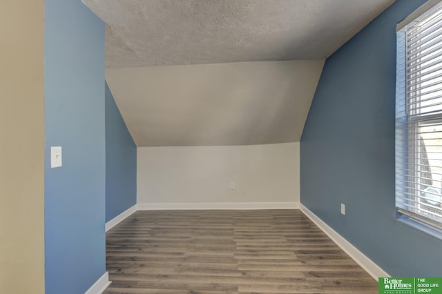 2864 Spaulding St, Omaha, NE 68111 - additional living space with lofted ceiling, a textured ceiling, baseboards, wood finished floors, and healthy amount of natural light
