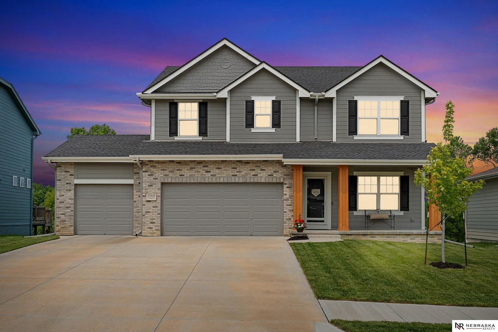 17618 Clay St, Bennington, NE 68007 - view of front of house with concrete driveway, a front yard, a porch, a garage, and brick siding