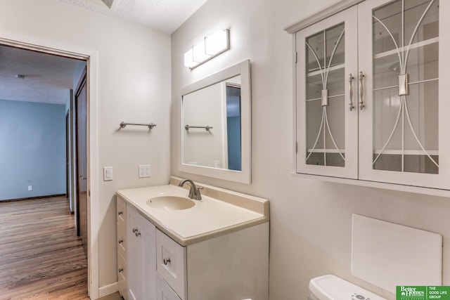 830 N 78th St, Omaha, NE 68114 - bathroom featuring vanity, toilet, wood finished floors, a textured ceiling, and baseboards