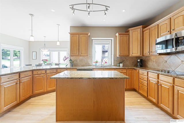 13303 Cuming St, Omaha, NE 68154 - kitchen with stainless steel microwave, light wood finished floors, a center island, and a sink