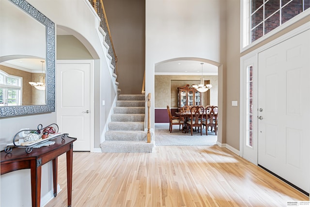 13303 Cuming St, Omaha, NE 68154 - entryway with a chandelier, arched walkways, wood finished floors, stairs, and a high ceiling