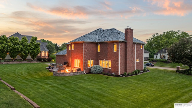 13303 Cuming St, Omaha, NE 68154 - back of house at dusk featuring an outdoor fire pit, a yard, a chimney, and brick siding