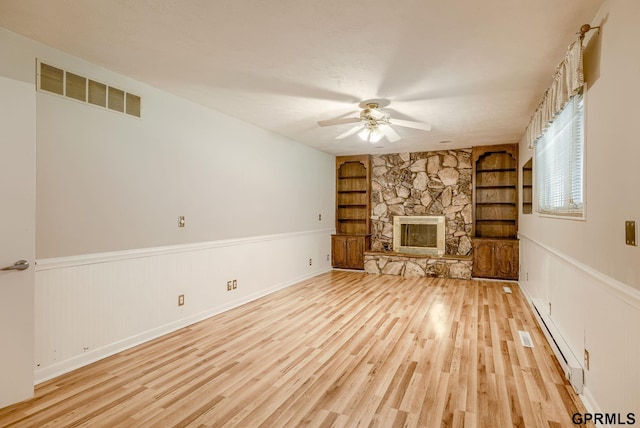 5617 S 93rd St, Omaha, NE 68127 - unfurnished living room with built in shelves, light wood finished floors, a baseboard radiator, a ceiling fan, and wainscoting
