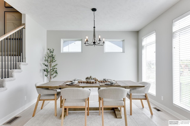 19920 Tyler St, Omaha, NE 68135 - dining area featuring a chandelier, healthy amount of natural light, light wood-style flooring, stairway, and a textured ceiling