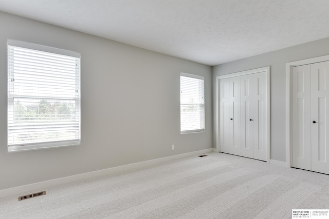 19920 Tyler St, Omaha, NE 68135 - unfurnished bedroom with light carpet, two closets, baseboards, and a textured ceiling