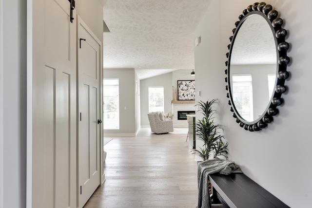 19920 Tyler St, Omaha, NE 68135 - hallway with a textured ceiling, light wood-type flooring, a barn door, lofted ceiling, and baseboards