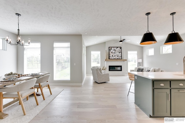 19920 Tyler St, Omaha, NE 68135 - kitchen featuring light wood-style floors, a glass covered fireplace, a chandelier, gray cabinets, and a textured ceiling