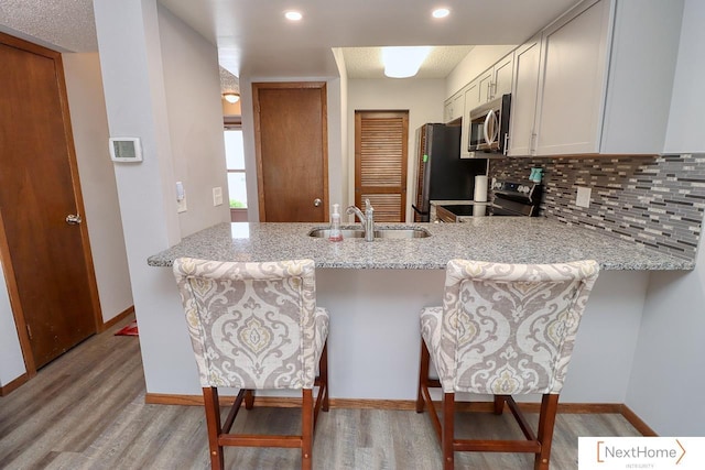 4115 N 45th Street Ct, Lincoln, NE 68504 - kitchen featuring appliances with stainless steel finishes, a sink, a peninsula, light wood-type flooring, and recessed lighting
