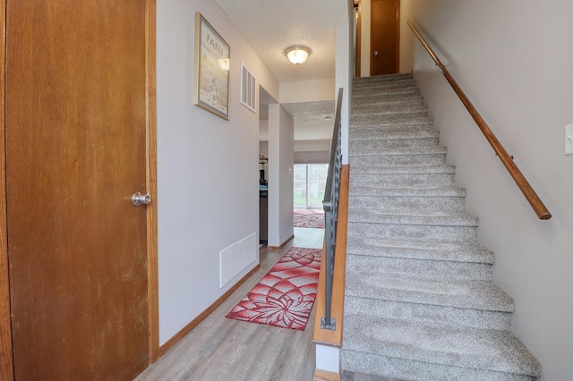 4115 N 45th Street Ct, Lincoln, NE 68504 - staircase featuring a textured ceiling, wood finished floors, and baseboards