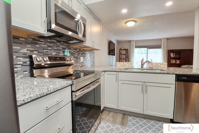 4115 N 45th Street Ct, Lincoln, NE 68504 - kitchen with stainless steel appliances, a sink, light wood-style floors, decorative backsplash, and a textured ceiling
