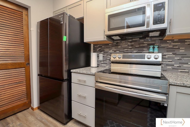 4115 N 45th Street Ct, Lincoln, NE 68504 - kitchen with appliances with stainless steel finishes, tasteful backsplash, light wood finished floors, and light stone counters